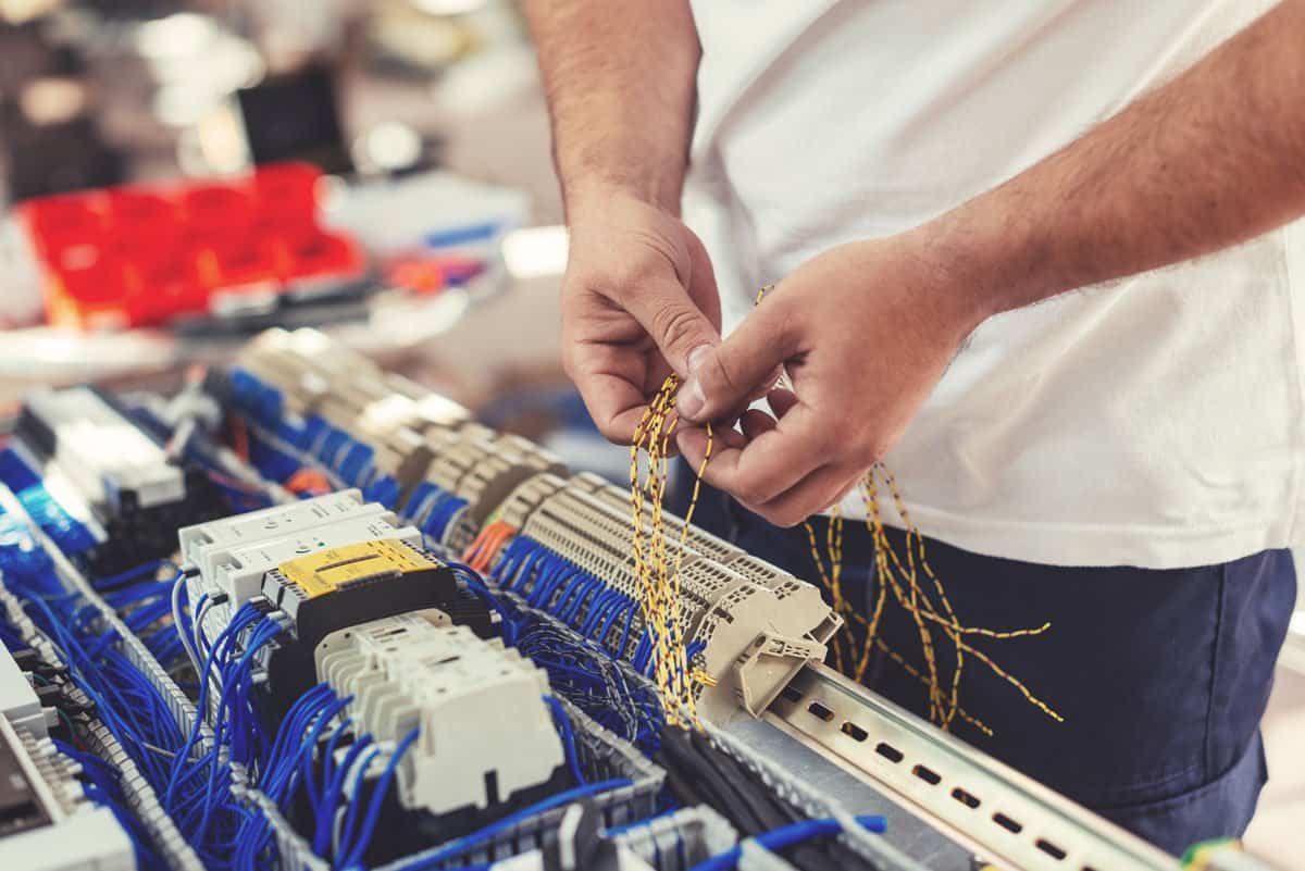 Technician wiring an industrial electrical control panel following safety standards in Oklahoma City.