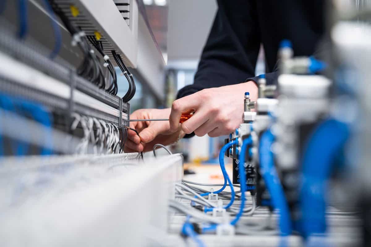 Technician installing wiring inside an industrial electrical control panel for automation systems in Oklahoma City.